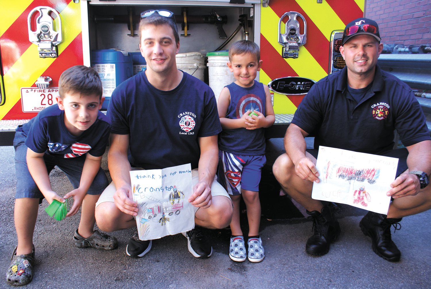 AN ARTISTIC THANK YOU: The Forte Brothers – Rocco, 7, and Luca, 4, – pose with firefighters Alex Cardoso and Corey Rebello who are holding drawings given to them by Rocco and Luca.